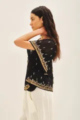 Blusa de gasa negra con escote en V, mangas amplias de largo irregular y bordados detallados con canutillos, lentejuelas y mostacillas. Incluye viso al tono con breteles regulables.