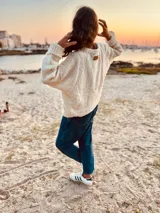 Sweater tejido en boucle color crema, de corte holgado y mangas largas.