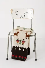 Bufanda extra large tejida a mano en 100% lana merino, con diseño jacquard inspirado en la tradición textil que presenta escenas campestres con ciervos, pequeños personajes y detalles florales.