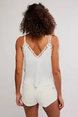 Camisola negra de satén con tirantes finos ajustables, escote en V y detalles de encaje floral en el contorno del pecho y los laterales. Presenta pequeñas aberturas laterales.