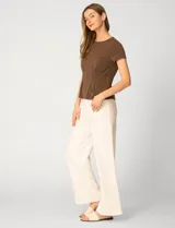 Remera blanca de manga corta con cuello redondo, confeccionada en una mezcla de modal, poliéster y elastano. Presenta un diseño con alforzas verticales en el frente que aportan estructura y una silueta relajada.