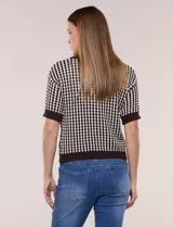 Cardigan de punto con patrón geométrico bicolor en gris y blanco, de manga corta, cuello polo y cierre frontal con botones nacarados.