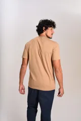 Remera de manga corta con cuello redondo, confeccionada en algodón de color beige. Presenta un pequeño logo bordado de un pingüino en el pecho.
