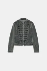 Chaqueta entallada de terciopelo color gris con efecto acid wash, cuello subido, manga larga y cierre frontal con ganchos metálicos. Presenta detalles de pasamanería con falsos botones en el delantero de inspiración militar.