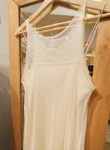 Vestido de red color crudo, con escote alto y largo midi. Incluye un forro interior independiente más corto, con escote recto y breteles finos.