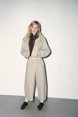 Sudadera tipo bomber de tejido suave, color beige, con cuello alto ajustable mediante cordones, cierre frontal con cremallera, mangas largas con puños elásticos y bolsillos laterales de vivo.