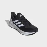 Championes de running Adidas Ultrarun 5, color negro con tres franjas blancas características en el lateral. Presentan una suela gruesa blanca con textura y detalles en negro en la parte inferior.