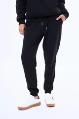 Pantalón de jogging de felpa color negro, con cintura elástica ajustable mediante cordón y puños acanalados en los tobillos.