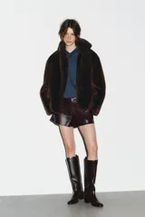 Bota alta de caña media en color marrón oscuro, con diseño minimalista, punta redonda y tacón bloque de madera. Cuenta con tirador trasero para facilitar el calce.