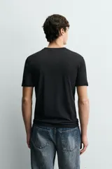 Camiseta blanca de algodón con elasticidad, corte slim fit, cuello en V y mangas cortas.