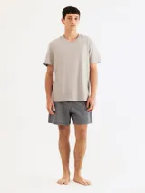 Pijama masculino compuesto por una remera gris de cuello V y un short azul con rayas verticales blancas.