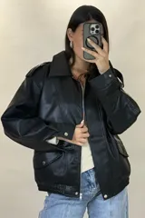 Chaqueta de ecocuero color marrón, de corte oversize, con cuello clásico, cierre frontal metálico, bolsillos laterales con solapa y puños con broches a presión.