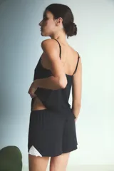 Conjunto de pijama compuesto por una musculosa con escote en V profundo decorado con encaje blanco y un short a juego. El diseño es de color negro, con breteles finos y corte holgado.
