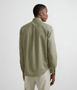 Camisa de manga larga confeccionada en sarga de algodón, con cuello clásico, cierre frontal abotonado y dos bolsillos frontales con solapa y botón.