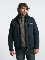 Campera técnica de tejido elástico en color azul marino, con capucha ajustable, cierre frontal y bolsillos laterales con cierre. Cuenta con forro interior de micro polar y ajuste en el ruedo.