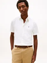 Camisa de manga corta Tommy Hilfiger confeccionada en tejido de popelina de algodón con tecnología flex. Presenta cuello clásico, cierre frontal con botones y el logo de la marca bordado en el pecho.