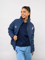 Campera puffer corta de Umbro para el Club Nacional de Football, color azul marino con diseño termosellado. Cuenta con cuello alto, cierre frontal con botones a presión, bolsillos laterales y logo de la marca junto al escudo del club en el pecho.