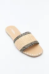 Sandalias planas color beige, con capellada ancha de tejido trenzado con texturas naturales y detalles de hilo contrastante.