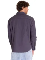 Camisa de manga larga marca Caterpillar, color violeta oscuro, con tres bolsillos de carga en el pecho con cierre de solapa y logo de la marca en el bolsillo izquierdo.