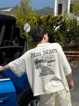 Remera marrón de corte holgado con estampado en la espalda que incluye texto y paisaje.