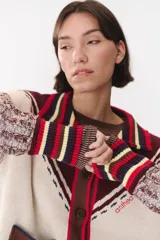 Cardigan de punto con diseño multicolor, cuello tipo polo con rayas, cierre frontal con botones y bolsillos aplicados. Presenta mangas con trama trenzada, coderas en contraste y bordado de la marca en el frente.