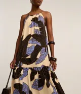 Vestido midi evasé de viscosa color beige con estampa de follaje en tonos marrones y celestes, diseño de frente única con tirantes finos.