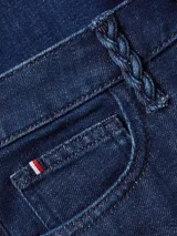 Jean azul oscuro de corte ajustado y talle alto, con trabillas trenzadas, diseño de cinco bolsillos y logo bordado en el bolsillo trasero.