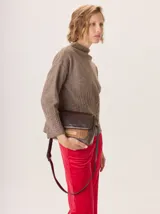 Cartera tipo bandolera de cuero, con solapa frontal que combina texturas lisas y grabadas en tonos marrones. Presenta una correa larga ajustable y detalles de costuras a la vista.