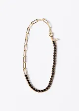 Pulsera dorada con una mitad de eslabones tipo clip y otra mitad con una hilera de zirconias negras.