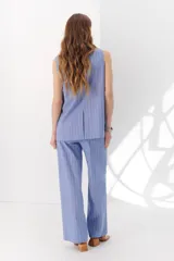 Chaleco largo color blanco con rayas verticales finas color beige, con cuello en V y cierre frontal con botones marrones. Incluye pañuelo al cuello con estampado de lunares y rayas.