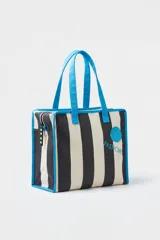 Cartera tote bag con diseño de rayas verticales en negro y blanco, asas de hombro y ribetes en color celeste. Cuenta con cierre superior y estampa con el nombre de la marca.