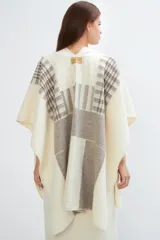 Ruana tejida con diseño de bloques en tonos tierra y beige, con cuello en V y terminación de crochet artesanal.