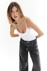 Jean negro gastado de corte recto, con costuras blancas contrastantes y bolsillos delanteros y traseros.