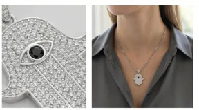 Collar con cadena de acero y dije en forma de mano de Hamsa, cubierto de circonias blancas con un detalle central de piedra negra en forma de ojo.