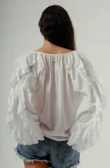 Blusa blanca de manga larga con volados en los puños y escote en V con botones frontales.