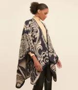 Poncho mediano con abertura delantera, confeccionado en tejido de punto con estampa de arabescos en tonos azul marino y beige.