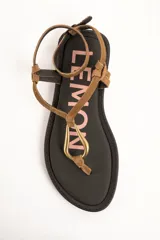 Sandalias planas de cuero color marrón, con tiras finas de gamuza, hebilla de ajuste en el tobillo y detalle de argolla metálica dorada en el empeine.