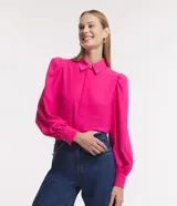 Camisa celeste de crepé con cuello inglés, manga larga abullonada y abotonadura frontal.