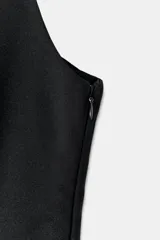 Top negro ajustado al cuerpo con escote recto y tirantes finos. Presenta un bajo con corte peplum.