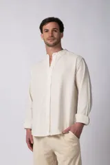 Camisa de manga larga confeccionada en lino, con cuello mao y cierre frontal de botones. Presenta un corte relajado y diseño minimalista.