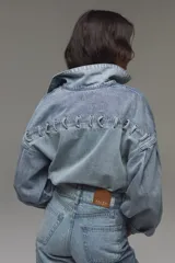 Campera de denim de algodón con diseño boxy, mangas abullonadas y detalles de cordones trenzados en la parte frontal.