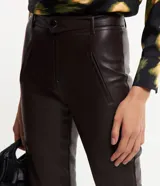 Pantalón skinny de cuero sintético color marrón oscuro, con cierre y botón en la cintura, bolsillos delanteros y traseros, y recortes en las rodillas.