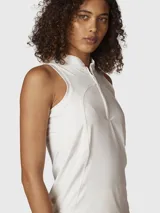 Conjunto deportivo compuesto por una musculosa blanca sin mangas con cuello alto y cierre frontal, y una pollera blanca con borde inferior en contraste negro.