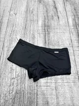 Short de baño tipo culotte de color negro, de tiro medio con detalle de placa metálica decorativa en el lateral.