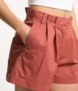 Short de sastrería confeccionado en tricolina de algodón, con diseño de tiro medio, pliegues delanteros, bolsillos laterales y bajo con dobladillo plegado. Cuenta con cierre de botón y cremallera, además de trabillas en la cintura.