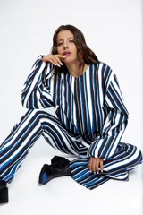 Campera tipo bomber corta, con cierre frontal, cuello a la base, bolsillos ojal y mangas largas abullonadas. Presenta un diseño estampado a rayas verticales en tonos azul, blanco y negro.