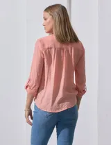 Blusa blanca de gasa marca Zac & Rachel, con cuello a la base, escote en V, abertura central con botones, bolsillo aplicado en el pecho y mangas largas regulables con presilla y botón. Tiene terminación opcional de nudo en el ruedo.