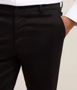 Pantalón slim de sastrería de color gris claro, confeccionado en sarga de algodón con elastano, con cierre frontal de botón y cremallera, y bolsillos.