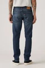 Pantalón de jean azul oscuro, corte slim fit, con pierna cónica y tiro medio. Diseño clásico de cinco bolsillos.