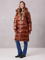Campera puffer larga de abrigo marca BCBG Maxazria, color beige. Cuenta con capucha desmontable, cuello alto envolvente, cierre frontal bidireccional con solapa de botones a presión, bolsillos laterales, puños internos elastizados y tajos laterales con cierre en el bajo.